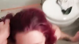 Busty redhead sucking the skinny guy's cock in the bar bathroom